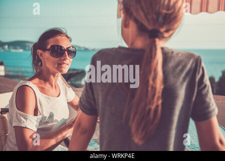 Mère fille parler avec le port de lunettes de soleil sur balcon Banque D'Images