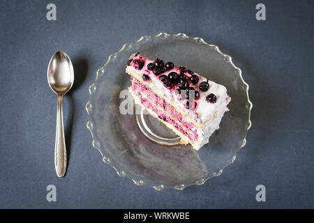 Morceau de gâteau aux bleuets et cuillère sur fond bleu Banque D'Images