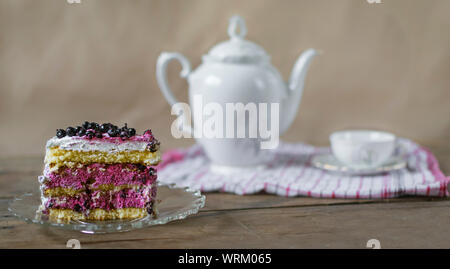 Morceau de gâteau aux bleuets sur table en bois avec tasse de thé en arrière-plan. Banque D'Images