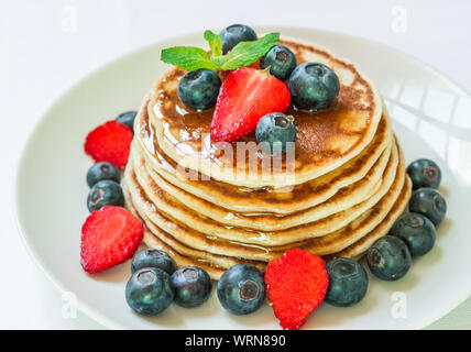 Des crêpes avec du miel américain contre l'arrière-plan blanc. Banque D'Images