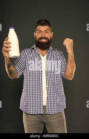 Les produits laitiers sont de bonnes sources de protéines et de calcium. Homme barbu tenant une bouteille de boisson laitière sur fond gris. Régime alimentaire des produits laitiers bénéficiant d'hipster heureux. Menu des produits laitiers. Banque D'Images