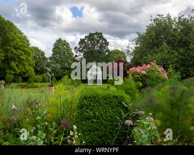 Chenies Jardin du Manoir à la recherche vers le parterre et blanc en juin avec la pagode birdcage et topiaire sculpture acrobatique. Banque D'Images