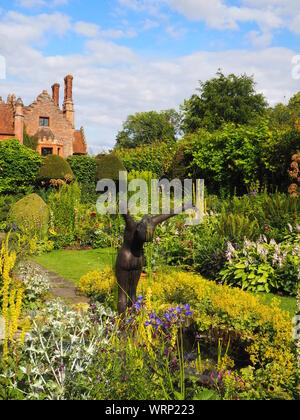 Portrait de Chenies manoir et jardin en contrebas, bassin d'agrément avec Alan Biggs' sculpture;f resh plante verte frontière en fin d'après-midi de juin. Banque D'Images