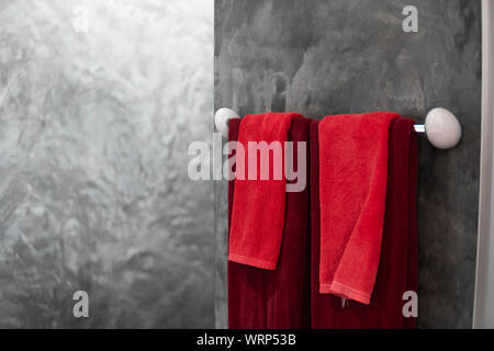 Deux serviettes de bains en rouge sur un sèche-linge. Salle de bains contemporaine contre l'intérieur. Luxe et design élégant, une salle de bains privative avec un style béton des murs. Banque D'Images