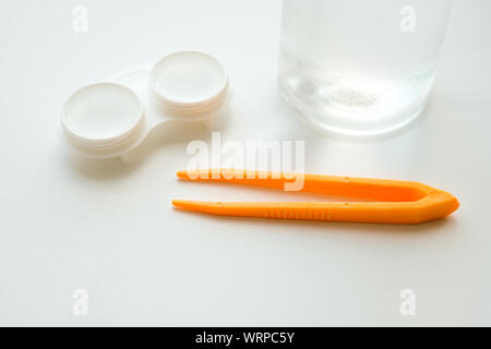 Accessoires pour une utilisation correcte des lentilles de contact : boîtier, brucelles et flacon de solution sur fond blanc. Correction de la vision en toute sécurité. Mise au point sélective. Banque D'Images