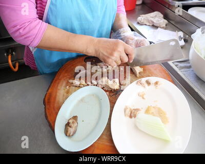 Les femmes asiatiques d'âge moyen de la viande de poulet cuit haché sur une planche à découper en bois, la vente dans le magasin de riz de poulet en Thaïlande Banque D'Images