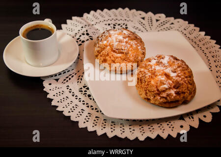 Crème de choux ou chou à la crème et café sur fond sombre. Focus sélectif. Banque D'Images