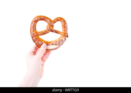 Woman's hand holding bavarois traditionnel bretzel salé isolated over white background Banque D'Images