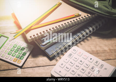 L'utilisation de portables dans un marais avec des crayons et calculatrices sur table en bois sous la lumière, de l'éducation concept. Banque D'Images