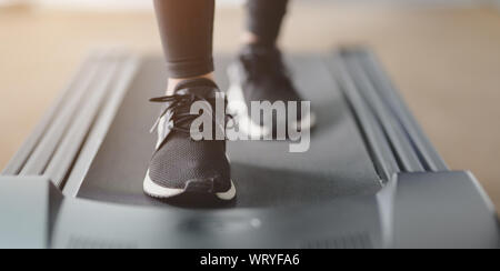 Close-up view of athletic woman jogging sneakers sur tapis roulant à l'intérieur de la salle de sport Banque D'Images