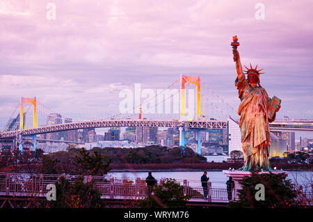 DEC 5, 2019 Tokyo, Japon - Odaiba pont Rainbow et statue de la liberté avec la lumière colorée et lumineuse avec vue sur la baie de Tokyo à soir Ciel rosâtre Banque D'Images