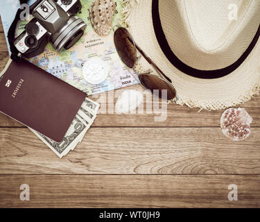 Concept de voyage avec un appareil photo numérique, chapeau de paille, lunettes de soleil, carte du monde, boussole, passeport, argent et coquillage sur table en bois Banque D'Images