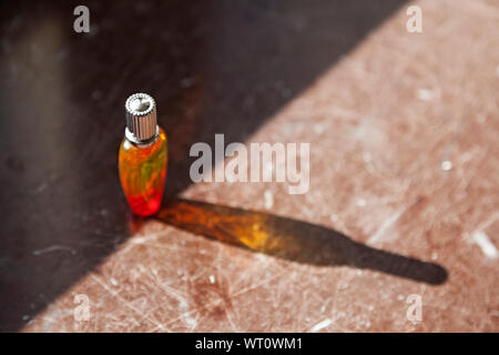 Flacon de parfum que le soleil brille à travers les couleurs et l'ombre qui tombe sur la table Banque D'Images