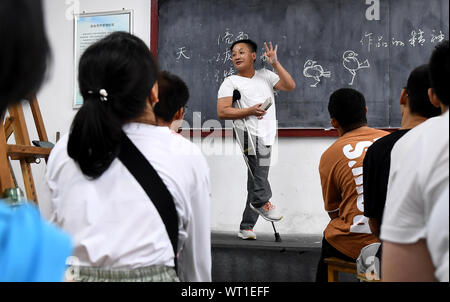 Beijing, Chine, Province du Shaanxi. Sep 9, 2019. Wang Xuyang, un professeur d'art, enseigne la peinture aux étudiants des connaissances s'est spécialisé en design graphique à l'École de l'économie urbaine de Shaanxi, une école professionnelle pour les étudiants handicapés, à Xi'an, province du Shaanxi du nord-ouest de la Chine, le 9 septembre, 2019. Wang contracté la polio comme un enfant, et ne pouvait marcher qu'avec l'aide d'une béquille. Credit : Liu Xiao/Xinhua/Alamy Live News Banque D'Images