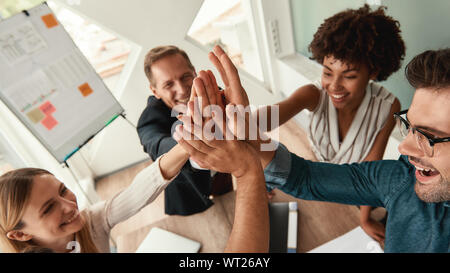 Bien fait les gens d'affaires donnant à chaque autres cinq et souriant tout en travaillant ensemble dans les bureaux modernes. Le travail d'équipe. Succès Banque D'Images