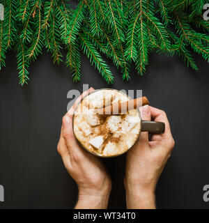 Boisson traditionnelle de Noël. Chocolat chaud avec des guimauves et la cannelle sur le fond noir avec la direction générale de l'arbre de Noël. Carte de vacances. Close up. Banque D'Images