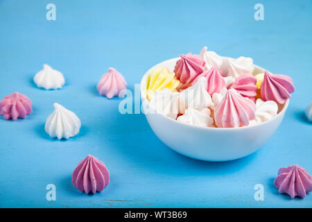 De délicieuses meringues blanc et rose sur un fond en bois bleu. Banque D'Images