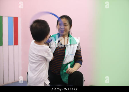 (190911) -- CHONGQING, le 11 septembre 2019 (Xinhua) -- professeur d'éducation spéciale s'Xianxi joue à des jeux avec un enfant à Chongqing Centre de réadaptation et de formation de la Jacinthe dans le sud-ouest de la municipalité de Chongqing en Chine, le 10 septembre, 2019. Né en 1990, enseignant de l'Ran Xianxi et Wang Huajun passé leur première journée des enseignants à Chongqing Centre de réadaptation et de formation Jacinthe mardi, après avoir quitté leurs emplois bien payés dans d'autres institutions de formation il y a deux mois. En combinant leur expérience professionnelle de psychologie appliquée et dévouement, leur travail acharné a été très apprécié par les t Banque D'Images