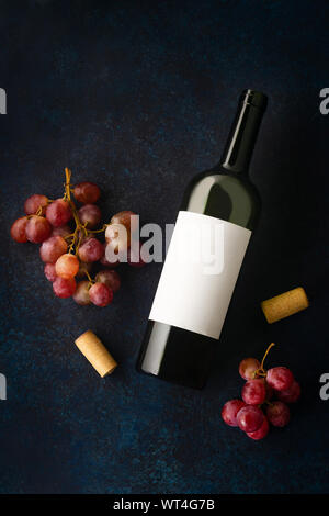 Flatlay avec bouteille de vin rouge, les bouchons et les raisins rouges sur fond bleu avec copie espace Banque D'Images