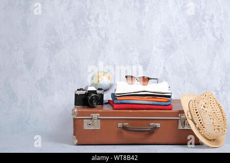 Valise de voyage à l'ancienne avec des accessoires : lunettes, pack de vêtements, appareil photo rétro, paille beach hat sur fond gris. Banner mocku Banque D'Images