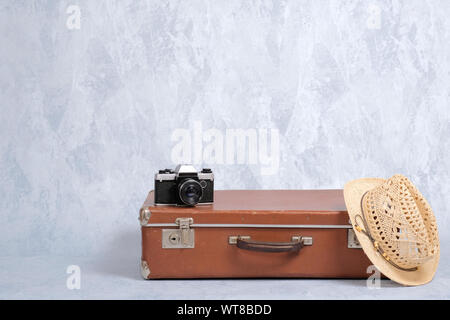 Les bagages de voyage, valise ancienne, chapeau de paille, appareil photo sur fond gris. Concept de voyage avec exploitation d'assurance, de voyage élégant, j Banque D'Images