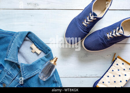 Regardez dans les vêtements élégants de style mises à plat sur un bureau en bois de couleur bleu pastel. Des vêtements décontractés, blogueur beauté fille hipster, jeune femme à la mode. Banque D'Images