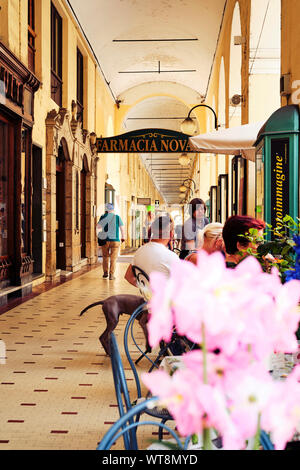 Le passage couvert jaune centre commercial avec boutiques et cafés dans la ville côtière d'Oneglia / Imperia sur la Riviera italienne en Ligurie, Italie. Banque D'Images