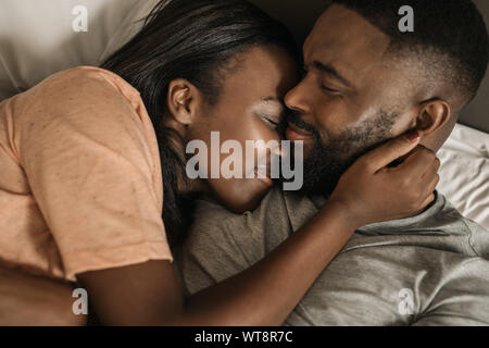 Smiling young African American couple hugging les uns les autres au lit Banque D'Images