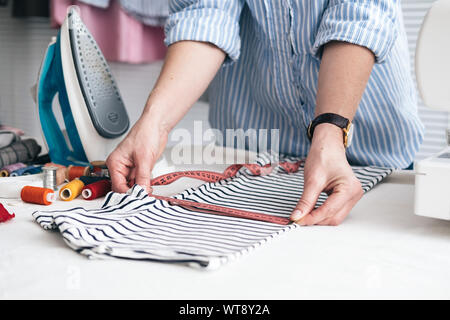 Jeune femme travaillant avec un ruban à mesurer à l'atelier de couture Banque D'Images