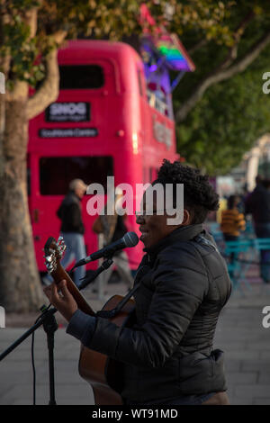 Chanteur musicien ambulant sur la rive sud de Londres de divertir les touristes sur une chaude journée d'été. Banque D'Images