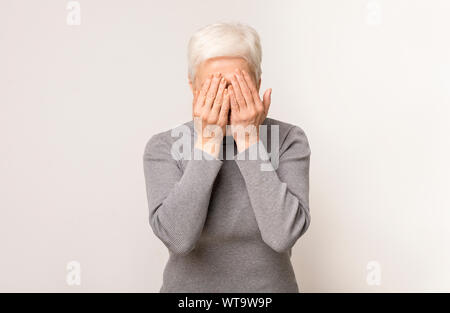 Portrait of senior woman peur couvrant les yeux avec les mains Banque D'Images