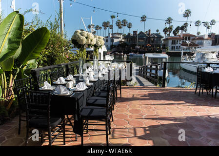 Serviettes pliées proprement en préparation pour grand groupe organisé le dîner sur une terrasse et donnant sur quai des bateaux du canal. Banque D'Images