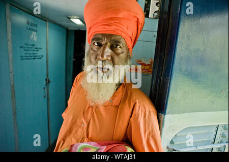 Dans Sikh orange élégant vêtements dans un train Banque D'Images