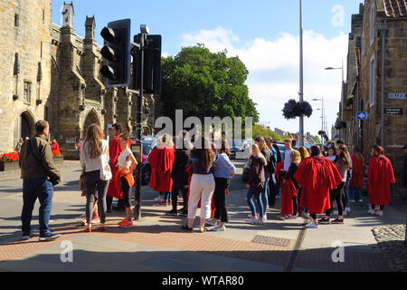 Un groupe d'étudiants de premier cycle à l'Université de St Andrews certains portant la robe rouge traditionnelle font leur direction St Salvator's Chapel sur North Street Banque D'Images