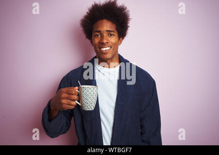 Pyjama homme vêtu de boire du café debout sur fond rose isolé avec un visage heureux et souriant debout avec un sourire confiant Banque D'Images