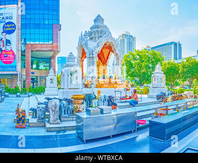 BANGKOK, THAÏLANDE - 24 avril 2019 : Le petit sanctuaire Trimurti avec gilden Ganesha assis à l'intérieur de l'alcôve, et de nombreuses sculptures en pierre d'éléphants Banque D'Images