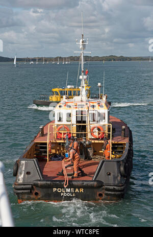 Le port de Poole, Dorset, England, UK. Septembre 2019. L'équipage du remorqueur tirant en ligne à partir d'un navire sur lequel ils ont juste tiré à partir d'un poste à quai. Banque D'Images