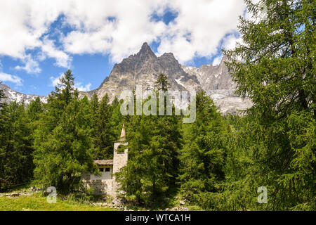 Paysage de montagne avec une église de pierre dans une forêt de pins au pied du massif du Mont Blanc en été, Val Ferret, Courmayeur, Aoste, Italie Banque D'Images