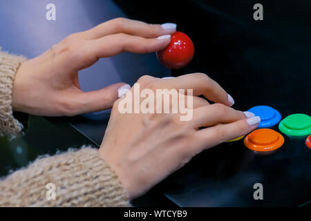 Gamer femme jouant de l'arcade rétro jeu de machine et en poussant les boutons lumineux Banque D'Images