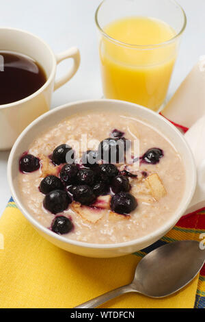 Gruau de céréales de petit-déjeuner avec les bleuets et les pommes hachées. Banque D'Images