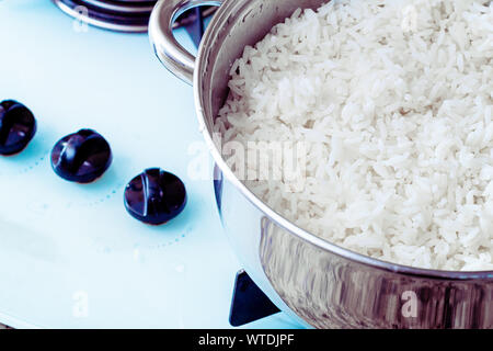 Photographie d'un poêle avec du riz bouilli sur table de cuisson. Banque D'Images