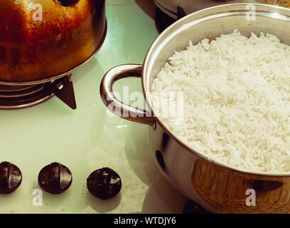 Photographie d'un poêle avec du riz bouilli sur table de cuisson. Banque D'Images