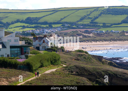 Couple marchant le long du sentier au-dessus de la baie de Croyde et de la plage de surf et de la station balnéaire de Croyde, North Devon, Angleterre, Royaume-Uni Banque D'Images