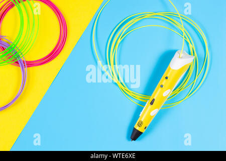 Stylo 3d avec des filaments de plastique en couleur sur fond jaune et bleu. Banque D'Images