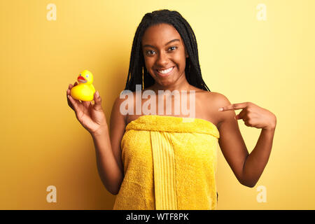 African woman holding serviette de douche canard sur fond jaune isolé avec surprise face à face à lui-même Banque D'Images