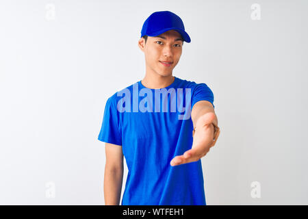 Livreur chinois portant des T-shirt bleu et le comité permanent sur fond blanc isolé offre amicale souriant et accueillant comme message d'handshake Banque D'Images