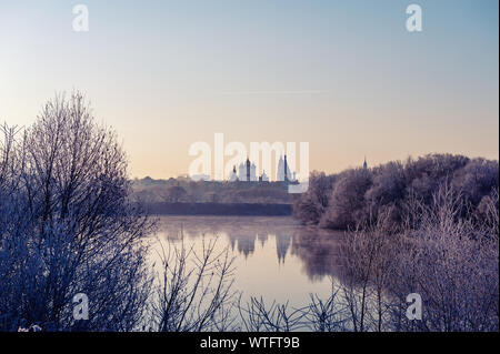 Paysage d'hiver des temples de la ville avec coucher de soleil sur la rive de la rivière. Les arbres sont couverts de neige, le soleil couchant illumine un beau Banque D'Images