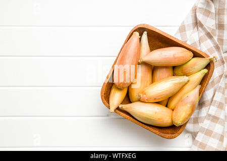 L'oignon l'échalote d'or. Bulbes frais dans un bol sur le tableau blanc. Vue d'en haut. Banque D'Images