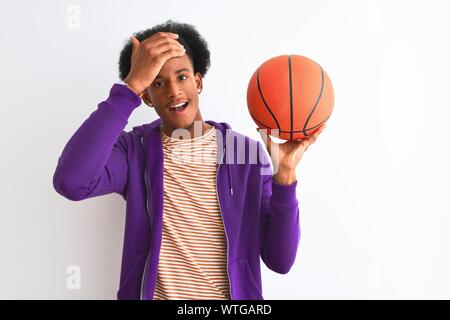 Young african american sportsman holding basketball ball sur fond blanc isolé a souligné avec la main sur la tête, choqué par la honte et la surprise fa Banque D'Images