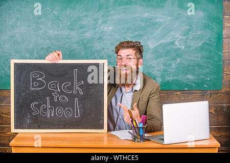 Enseignant ou directeur d'école accueille avec tableau noir inscription retour à l'école. Bienvenue à nouveau. Enseignant accueille de nouveaux élèves à entrer dans l'établissement d'enseignement. Début de nouvelle année scolaire en septembre. Banque D'Images